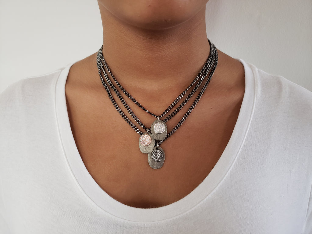 Girl wearing gray triple chain necklace . First layer has silver color disc and silver micro pave sz pendant.Second layer has silver disc and rose gold micro pave sz pendant.Third layer has silver disc and gunmetal micro pave sz pendant.