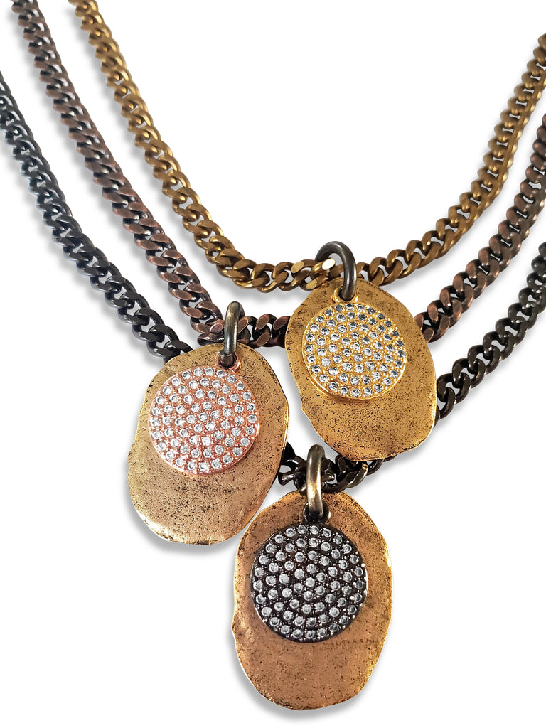 Triple chain necklace close up. First layer has brass chain and gold disc with gold micro pave sz pendant .Second layer has gray chain and gold disc with rose gold micro pave sz pendant.Third layer has gunmetal chain and gold disc with gunmetal micro pave sz pendant.